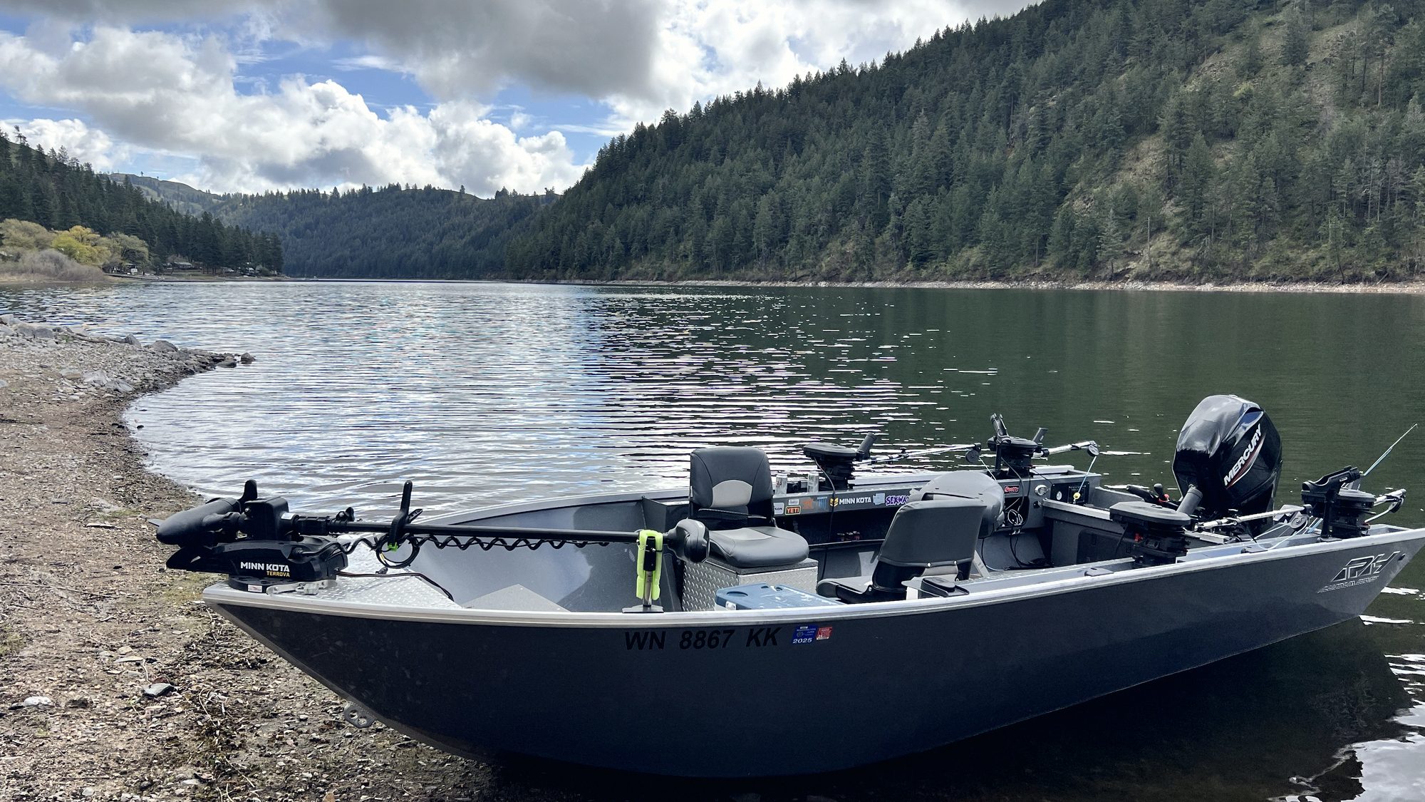 A boat pulled up on a gravel shore under heavy Pacific Northwest weather.